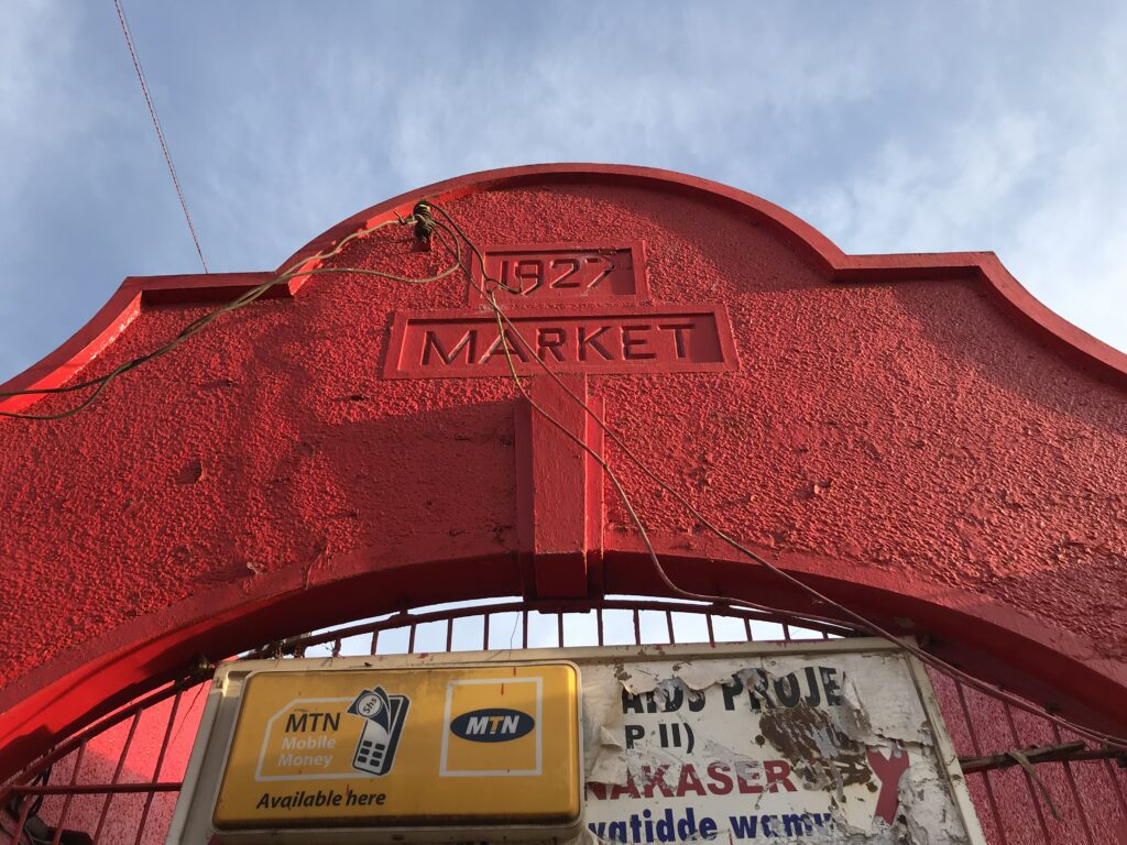 The red entrance arch of Nakasero Market in Kampala, with signs beneath it.