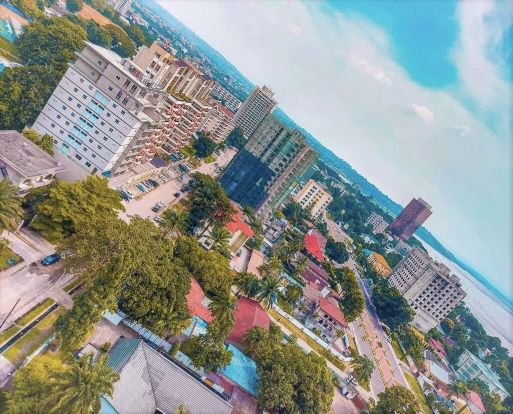 An elevated view across buildings, roads and trees in Kinshasa.